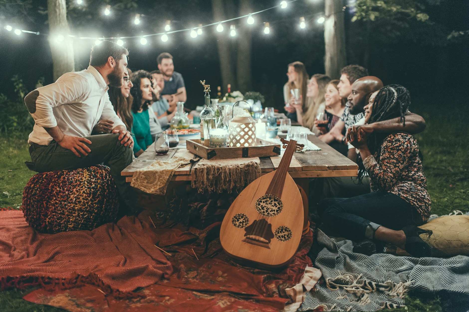 Friends gathered at a candlelit table under string lights